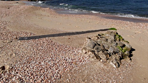 A pillar and building chunk partially buried in the sand